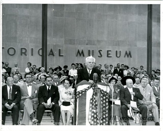 Bunche is pictured here seated between his wife, Ruth H. Bunche, and Michigan Governor G. Mennen Williams, at the dedication ceremony for the Detroit Historical Museum on July 24, 1951.
