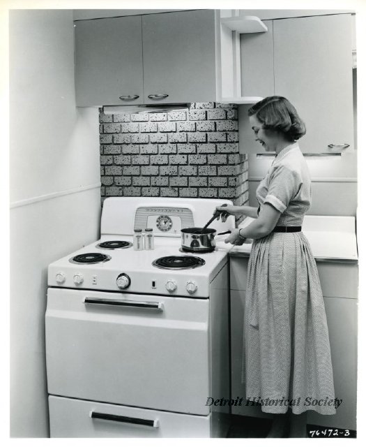 Photo showing a woman using a Kelvinator stove, 1958 - 2012.046.440