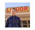 Man in a blue zip up jacket standing in front of a store front with a liquor sign. His head is blocking the letter Q.