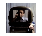Man holding a corded phone receiver to his ear, viewed through an old-fashioned television screen.